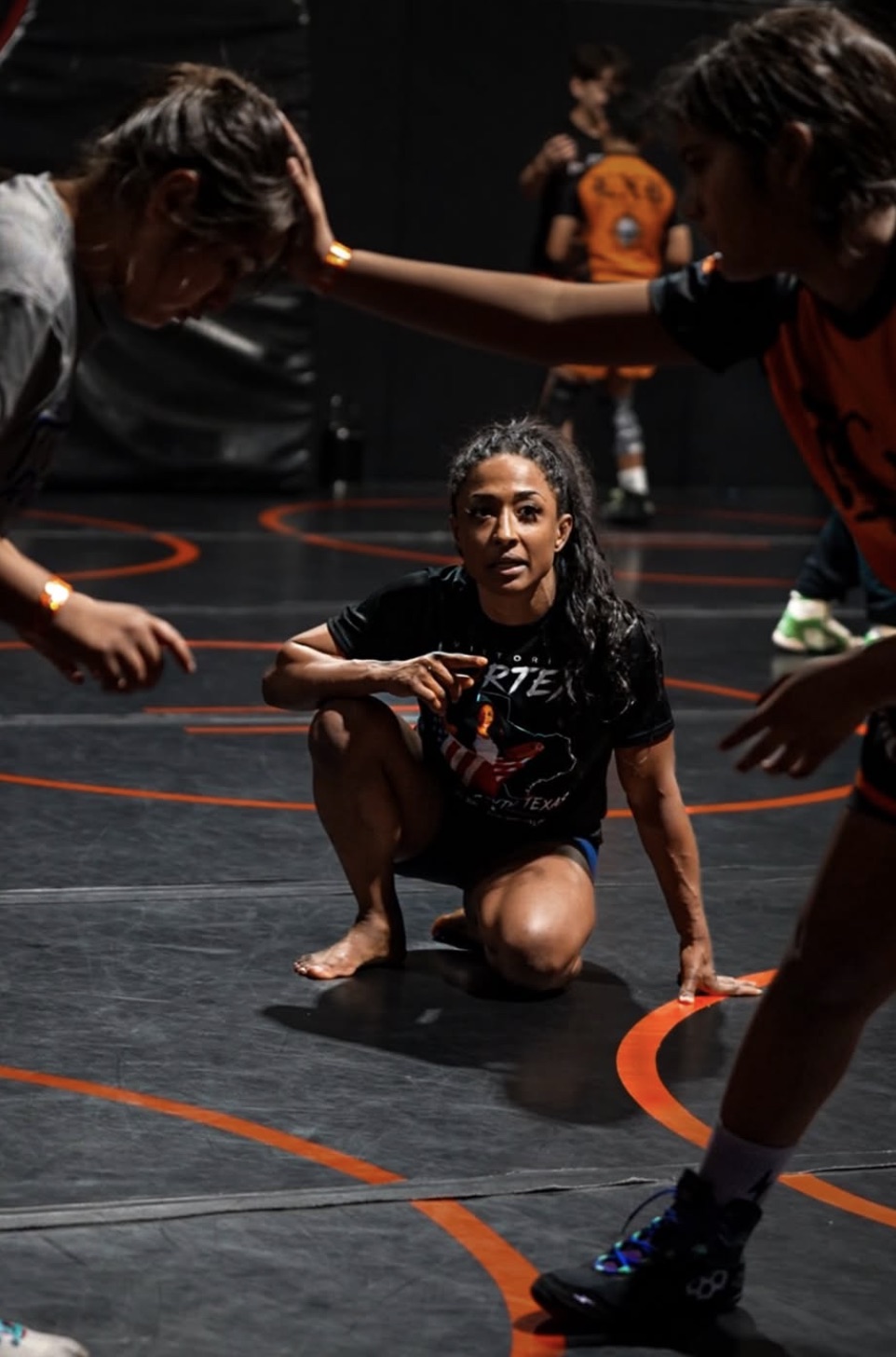 Victoria Anthony coaching young wrestlers on the mat
